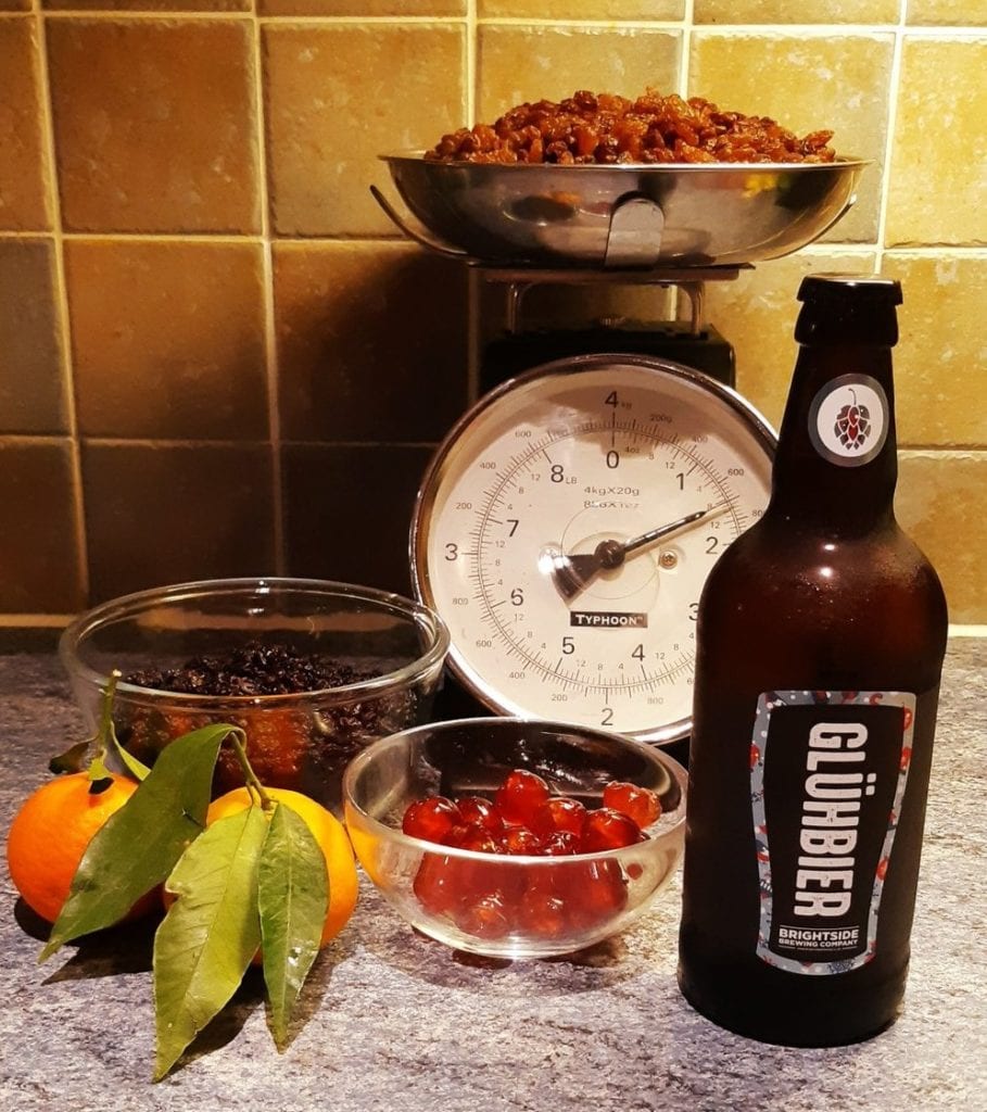 A 500ml bottle of Brightside Gluhbier beer with Christmas cake ingredients which include cherries raisins orange and bay leaf.